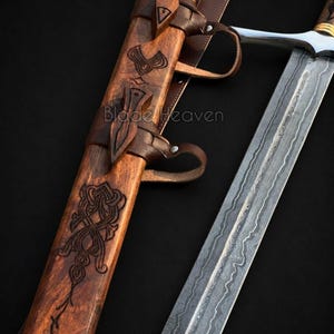 May include: A sword with a patterned Damascus steel blade and a wooden scabbard featuring intricate carvings and leather straps. The text Blade Heaven is visible on the scabbard and the lower right corner. The hilt has a silver crossguard.