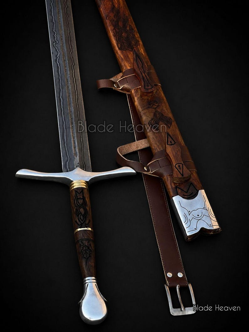 May include: A Damascus steel sword with a dark, wavy pattern on the blade, a wooden handle with intricate black carvings, gold-colored rings, and a silver pommel. It includes a matching wooden scabbard with leather straps and silver accents.