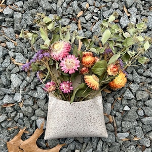 May include: A set of three ceramic mugs with a speckled, matte finish. The mugs are in shades of cream, light gray, and dark gray. Each mug has a simple, minimalist design and a rounded handle.