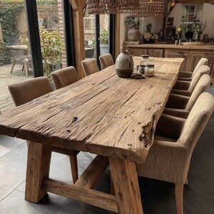 May include: A large, rustic wooden dining table with a natural, weathered finish. The table is supported by thick, sturdy legs and is surrounded by upholstered chairs. Decorative jars and a vase sit on the table. The table is approximately 305 cm long.