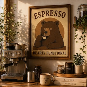 Puede incluir: Un letrero enmarcado con la palabra "ESPRESSO" encima de un oso de dibujos animados bebiendo café. El letrero también dice "BEARLY FUNCTIONAL". También se ve una máquina de espresso de acero inoxidable, tazas de café y granos de café.