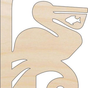 May include: A wooden pelican-shaped wall decor with a fish cutout in its beak. The pelican is light brown with a smooth finish and a decorative cutout design. The design includes a circular hole and several angled cutouts.