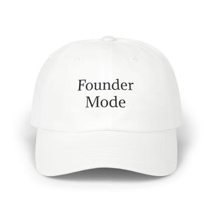 May include: A white baseball cap featuring the text Founder Mode printed in black serif font on the front panel. The cap has a structured crown, a curved brim, and a button on the top center, providing a clean and simple design for headwear.