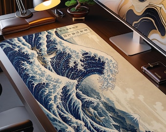 May include: A rectangular desk mat featuring a detailed print of a large, dark blue ocean wave with white foam crests, a small boat, and a mountain peak in the background. The design includes vertical Japanese text in a rectangular box at the top.