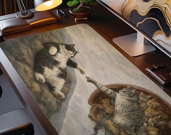 Puede incluir: Una alfombrilla de escritorio rectangular con una ilustración artística impresa de dos gatos extendiendo sus patas el uno hacia el otro. Un gato blanco y negro descansa sobre una roca, mientras un gato atigrado gris está rodeado de gatitos en un recipiente marrón.