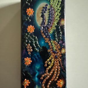 May include: Rectangular decorative item with a night sky design, featuring a full moon and a phoenix made of colourful rhinestones. Orange flower accents are scattered around the edges, creating a celestial theme.