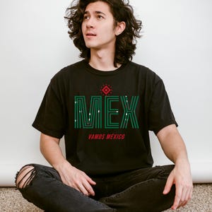 May include: Black t-shirt with the word "MEX" in green, with white accents, and the words "VAMOS M&Eacute;XICO" in red. The shirt has a geometric design above the word "MEX".