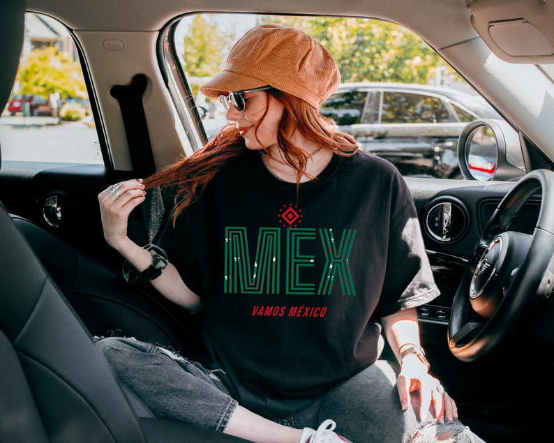 May include: Black t-shirt with the word "MEX" in green, with a red and white design above it and the words "VAMOS M&Eacute;XICO" below. The shirt is worn with a brown hat and sunglasses.
