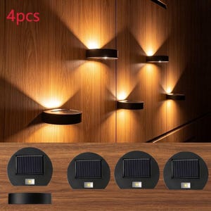 May include: A set of four black semi-circular solar wall lights. Each unit features a rectangular solar panel on top and a single LED light at the bottom. The lights are shown mounted on a wood-paneled wall, emitting a warm, upward and downward glow.