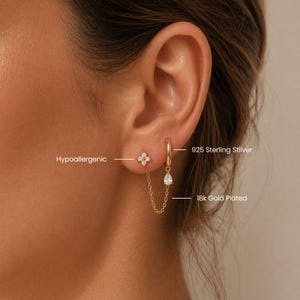 Peut inclure: Gros plan sur deux boucles d'oreilles. L'une est une petite puce d'oreille dorée avec un motif à quatre pétales et l'autre est un anneau doré avec un charm en forme de goutte. Le texte indique "925 Sterling Silver", "18k Gold Plated" et "Hypoallergenic".