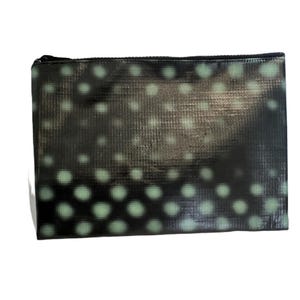May include: A rectangular black clutch bag featuring a repeating pattern of pale green polka dots. The bag has a black zip closure along the top edge. The material has a textured appearance.