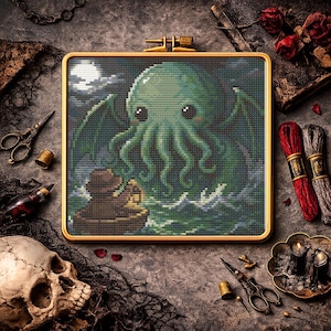 May include: Cross-stitch art of a green, tentacled creature with large eyes, wings, and a boat in the sea under a moonlit sky. The artwork is framed in a gold hoop. The scene is surrounded by sewing supplies and a skull.