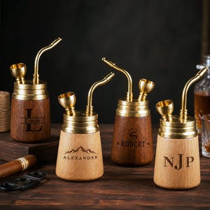 Puede incluir: Cuatro pipas de fumar portátiles con bases cilíndricas de madera y partes superiores de latón. Cada pipa cuenta con una boquilla de latón curvada y un hornillo. Las bases de madera están grabadas con los nombres Lucas, Alexander, Robert y las iniciales NJP.