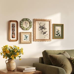 Può includere: Una composizione a parete con cinque opere d'arte incorniciate di varie texture e forme, tra cui una cornice verticale per foto, una cornice verde smerlata, una cornice quadrata con perline, una grande cornice rettangolare e una in velluto verde.