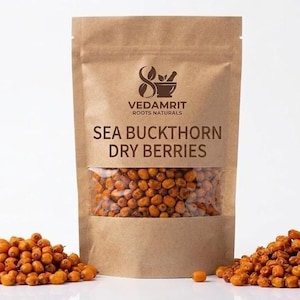 Könnte beinhalten: Ein brauner Papierbeutel mit getrockneten orangefarbenen Sanddornbeeren. Das Etikett trägt den Text VEDAMRIT ROOTS NATURALS und SEA BUCKTHORN DRY BERRIES. Ein Sichtfenster zeigt die Beeren, weitere lose Beeren liegen auf beiden Seiten.