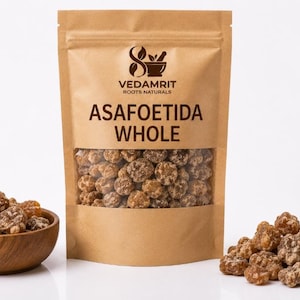 May include: A brown kraft paper stand-up pouch labeled VEDAMRIT ROOTS NATURALS ASAFOETIDA WHOLE with a clear window showing brown, resinous, lumpy pieces. A small wooden bowl filled with the same pieces sits to the left, and a pile sits to the right.