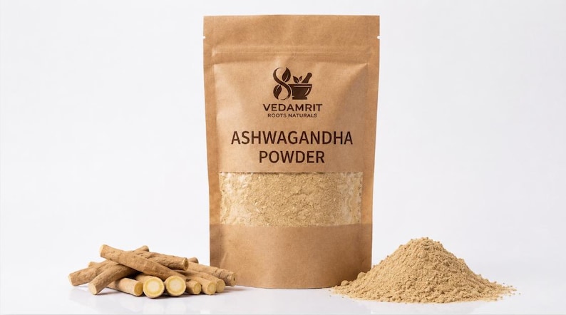 Może przedstawiać: Brązowa torebka z papieru pakowego z etykietą VEDAMRIT ROOTS NATURALS ASHWAGANDHA POWDER i przezroczystym okienkiem ukazującym jasnobrązowy proszek. Obok torebki leżą kawałki zdrewniałych korzeni oraz mały kopczyk drobnego, jasnego proszku.