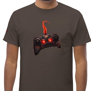May include: A dark brown short-sleeved t-shirt featuring a graphic of a black video game controller with glowing red eyes and a flame-like red plume rising from the top centre, positioned on the chest area of the garment.