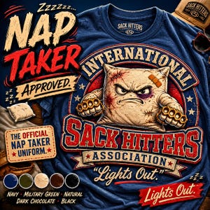 May include: Navy blue t-shirt with a graphic of an angry pillow wearing brass knuckles, a bandage, and stitches. Text includes "NAP TAKER APPROVED" and "SACK HITTERS INTERNATIONAL ASSOCIATION". Additional colors: military green, natural, dark chocolate, and black.