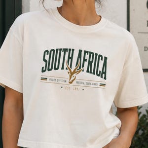 南アフリカラグビーシャツ、スプリングボックグラフィッククロップトップ、アマボコボコクロップドTシャツ、ラグビーディビジョンプレトリアシャツ、ヴィンテージボックスフィットラグビーTシャツ