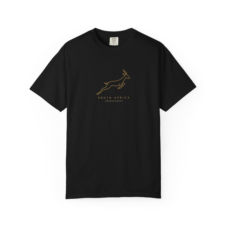A black t-shirt with a gold outline of a jumping springbok and the words "SOUTH AFRICA AMABOKOBOKO" below it, laid flat on a white background.