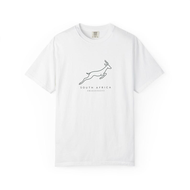 A white t-shirt with a black outline of a jumping springbok and the words "SOUTH AFRICA AMABOKOBOKO" below it, laid flat on a white background.