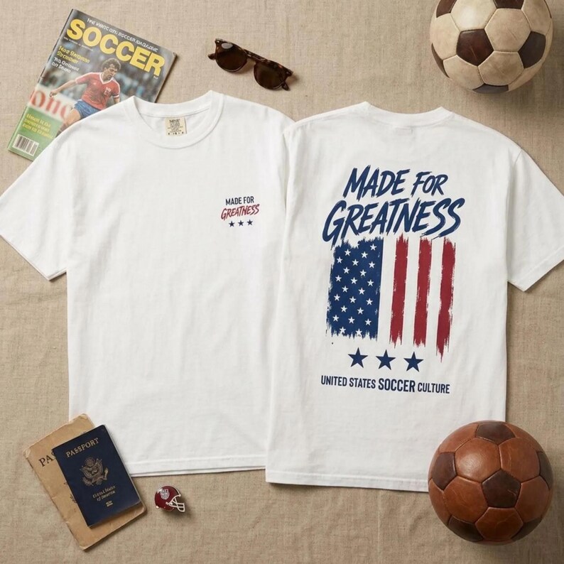以下が含まれることがあります： 前面に「MADE FOR GREATNESS」の文字と3つの星がデザインされた白いTシャツ2枚。背面には、かすれたアメリカ国旗のグラフィックと「MADE FOR GREATNESS」、「UNITED STATES SOCCER CULTURE」、そしてその下に3つの星がプリントされています。