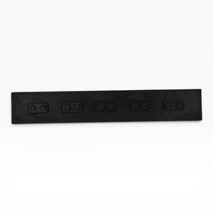 May include: A rectangular black wall-mounted coat rack featuring a textured surface. The rack includes five evenly spaced rectangular hooks, each designed with two circular pegs for hanging items. The entire piece is finished in a matte black.