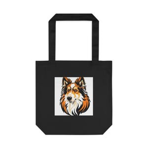 Op de afbeelding: Zwarte draagtas met een hondenillustratie. Het gezicht van de hond is afgebeeld in bruin, oranje en wit. De tas heeft twee zwarte handvatten en is gemaakt van duurzaam materiaal.