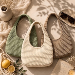May include: Three crochet handbags in sage green, cream, and tan colors. Each bag features a rounded hobo shape with a single integrated handle and a consistent horizontal ribbed texture throughout the exterior surface of the woven material.
