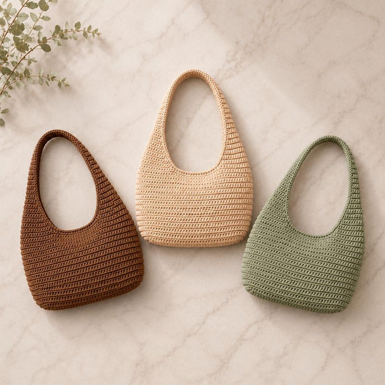 Peut inclure: Trois sacs &agrave; main de style hobo r&eacute;alis&eacute;s avec un point de crochet dense. Les sacs sont pr&eacute;sent&eacute;s en trois couleurs unies distinctes : un brun chocolat profond, un beige clair et un vert sauge att&eacute;nu&eacute;. Chaque sac poss&egrave;de une anse int&eacute;gr&eacute;e.