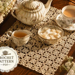 May include: A cream-coloured rectangular crochet doily featuring a repeating floral motif. The doily is displayed under a white porcelain teapot, a teacup with saucer, a creamer, and a bowl of sugar cubes. A circular label reads CROCHET PATTERN PDF.