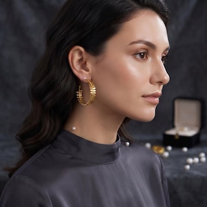 May include: A gold hoop earring featuring a delicate leaf-shaped design along the entire circular band. The earring is worn on the earlobe and has a matte finish, showcasing a detailed botanical pattern that follows the curve of the hoop structure.