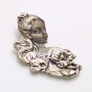 Könnte beinhalten: Silberfarbene Metallbrosche mit dem Profil einer Frau mit fließendem Haar und einem floralen Motiv. Die Brosche im antiken Stil ist vor einem weißen Hintergrund platziert und zeigt ihre filigranen Details.