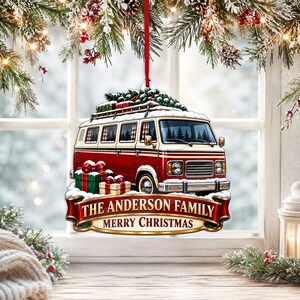 May include: A flat, hanging Christmas ornament featuring a red and white vintage van topped with a Christmas tree. The van is surrounded by wrapped gifts and snow. A gold-trimmed red banner at the bottom reads THE ANDERSON FAMILY MERRY CHRISTMAS.