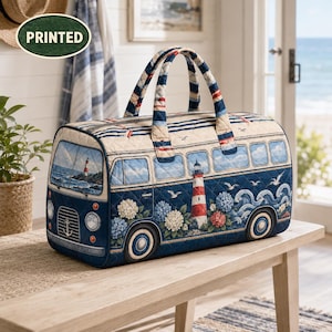 May include: A quilted duffel bag shaped like a vintage bus, featuring a navy blue and cream colour palette. The design includes a lighthouse, hydrangea flowers, ocean waves, and seagulls. It has two top handles and a zip closure along the top.