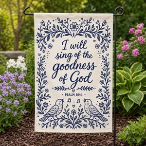 May include: A rectangular garden flag with a cream background and dark blue ink. The text reads, I will sing of the goodness of God, Psalm 89:1. The design features a floral border, two birds facing each other, and musical notes.