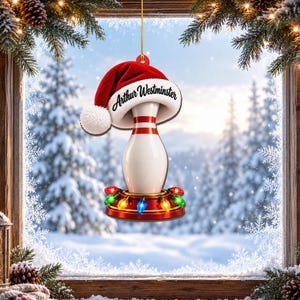 Op de afbeelding: Een kerstornament in de vorm van een bowlingkegel met een rode kerstmuts met een witte pompon en rand. De naam Arthur Westminster staat op de muts gedrukt. De kegel staat op een ronde voet versierd met kleurrijke, gloeiende kerstlampjes.