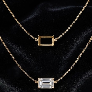 Peut inclure: Deux colliers en or avec des chaînes fines. Le collier du haut présente un sertissage métallique rectangulaire vide. Le collier du bas comporte une pierre précieuse transparente rectangulaire taille émeraude dans un cadre en or assorti.