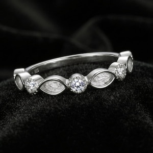 May include: A silver-coloured ring featuring a repeating pattern of round, clear, faceted stones alternating with marquise-shaped, textured silver settings. The inner band is clearly stamped with the hallmark 925, indicating sterling silver composition.