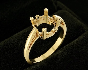 Op de afbeelding: Een ring van gepolijst geelgoud met een ingewikkelde, opengewerkte kop in kroonstijl, ontworpen om een edelsteen vast te houden. De band is glad en massief en leidt naar een decoratieve, filigraan-geïnspireerde galerij die de centrale klauwen ondersteunt.
