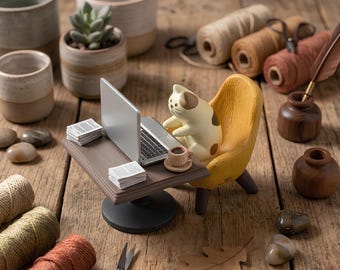 Figura de gato en miniatura con portátil, divertida decoración para el escritorio donde se trabaja desde casa.