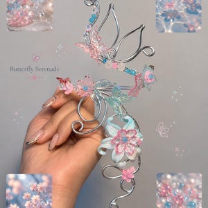 May include: A silver-toned hair accessory with a floral and butterfly design. The piece features pink, blue, and clear accents, including beads and flower-shaped embellishments. A small silver horse charm hangs at the bottom. The text "Butterfly Serenade" is also visible.