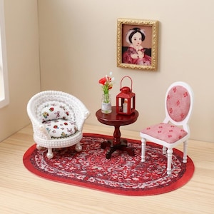 Può includere: Un set di mobili in miniatura per casa delle bambole composto da una poltrona bianca intrecciata con cuscino a fragole, un tavolino rotondo in legno scuro, una lanterna rossa, un piccolo vaso di fiori e una sedia bianca con seduta rossa.