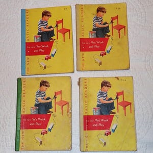May include: Four vintage children's books with yellow covers and colorful illustrations. The books are titled "The New Basic Readers" and feature the text "We Work and Play".