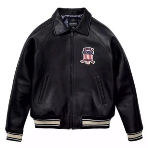 May include: A black leather jacket with a front zipper closure, a pointed collar, and two side pockets. The chest features an embroidered patch with the text AVIREX and a United States flag design. The cuffs and hem have black and white stripes.