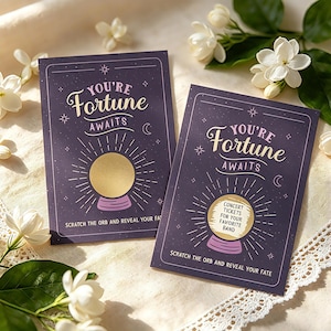 May include: Two purple fortune cards with gold scratch-off orbs. The cards read "You're Fortune Awaits" and "Scratch the orb and reveal your fate." One card offers concert tickets. White flowers and lace trim surround the cards.