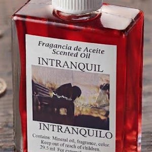 Puede incluir: Un frasco de vidrio rectangular lleno de aceite perfumado rojo brillante, con una tapa blanca estriada. La etiqueta blanca presenta el texto Fragancia de Aceite Scented Oil, INTRANQUIL, INTRANQUILO e indica un contenido de 29,5 ml.