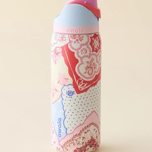 May include: A colorful Owala water bottle with a floral pattern in red, pink, and blue. The bottle has a light blue lid and a pink top. The word "owala" is printed on the bottle.