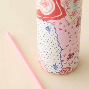 May include: A pink insulated tumbler with a floral and polka dot pattern, and a matching pink straw. The tumbler features a mix of red, pink, and blue floral designs, and a white polka dot pattern.